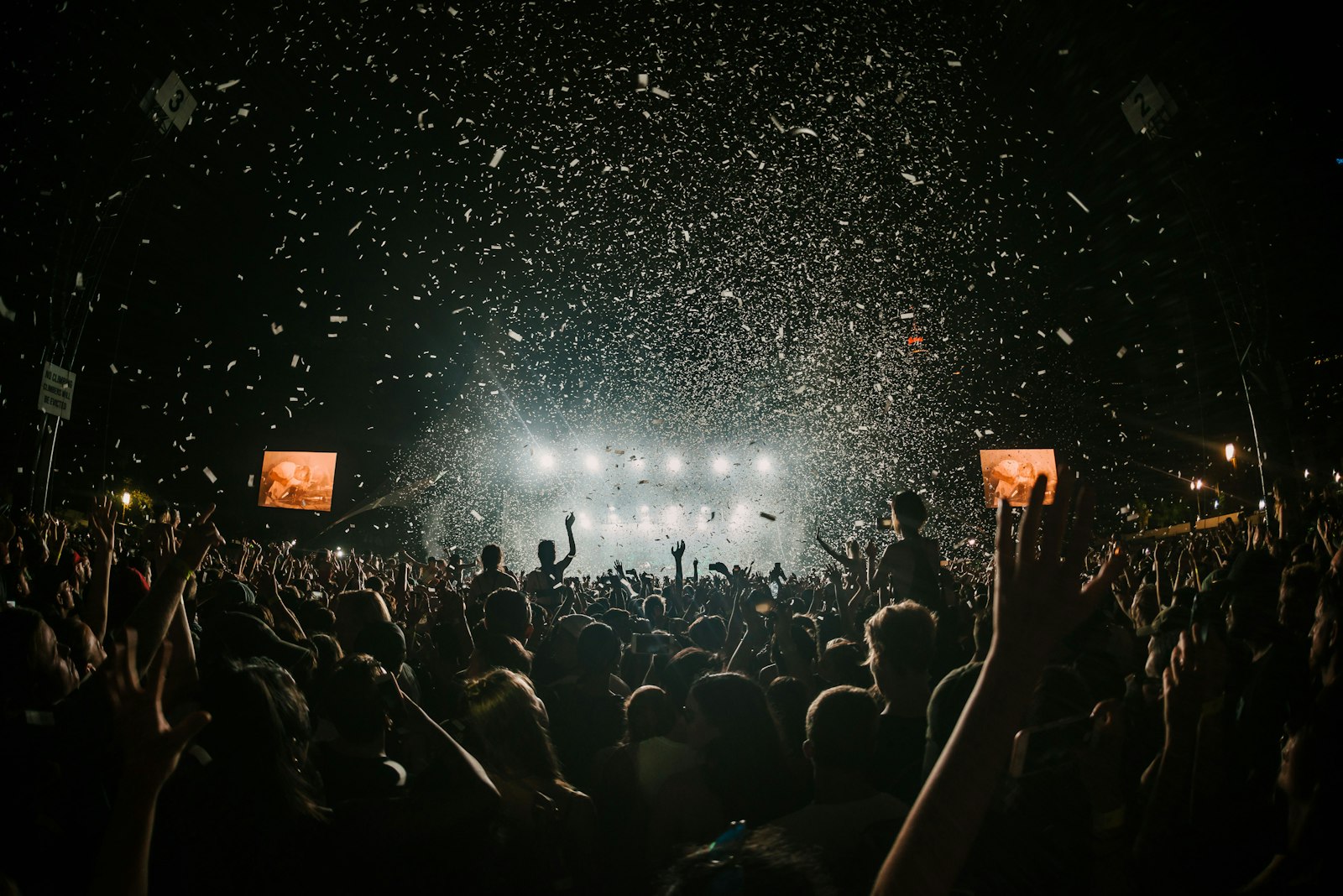 Confetti raining over a cheering crowd with hands raised